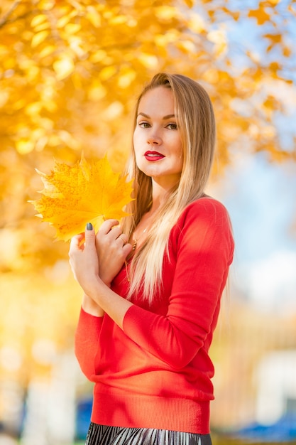 Concepto de otoño - hermosa mujer tomando café en el parque de otoño bajo el follaje de otoño