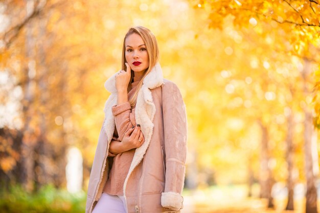 Concepto de otoño - hermosa mujer tomando café en el parque de otoño bajo el follaje de otoño