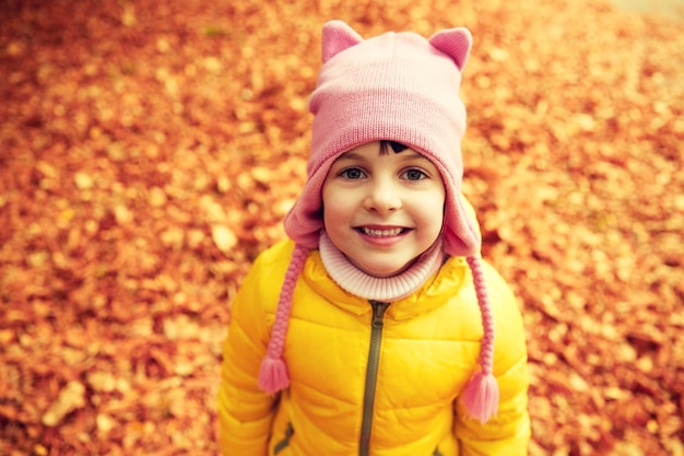 concepto de otoño, infancia, naturaleza y personas - niña feliz sobre hojas caídas en el parque