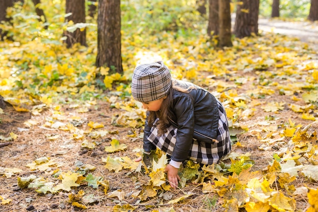 Concepto de otoño, infancia y temporada - Niña jugando en el parque de otoño