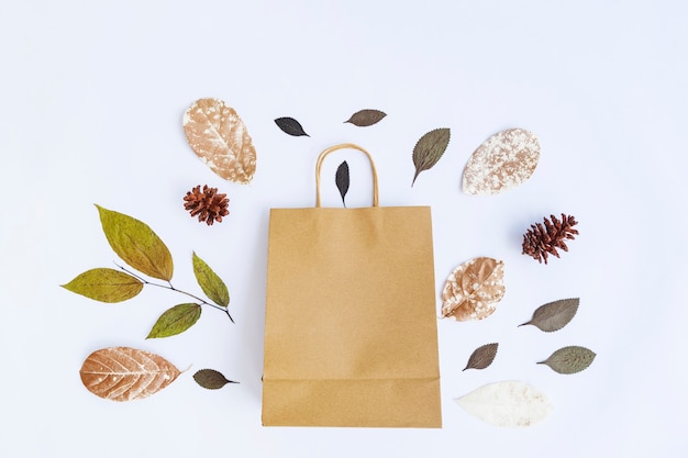 Concepto de otoño minimalista. Hojas secas, flores de pino, bolsas de papel aislado sobre fondo de papel blanco