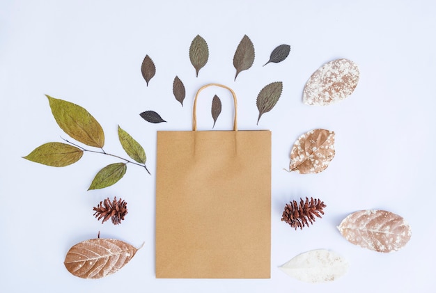 Concepto de otoño minimalista. Hojas secas, flores de pino, bolsas de papel aislado sobre fondo de papel blanco