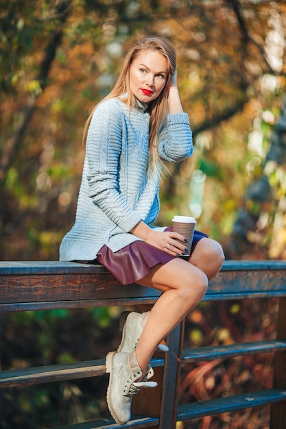 Concepto de otoño - mujer hermosa en el parque de otoño bajo el follaje de otoño