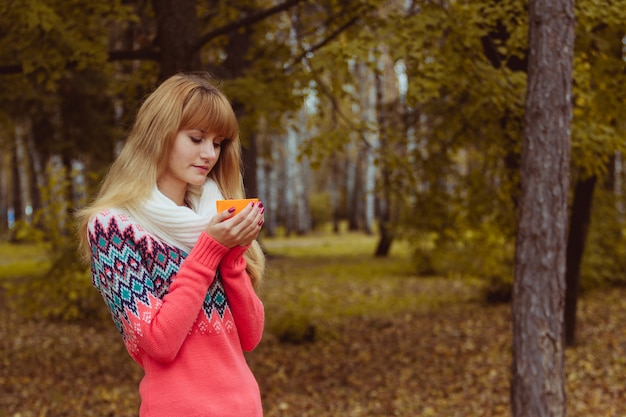 Concepto de otoño - mujer otoño bebiendo café en el parque