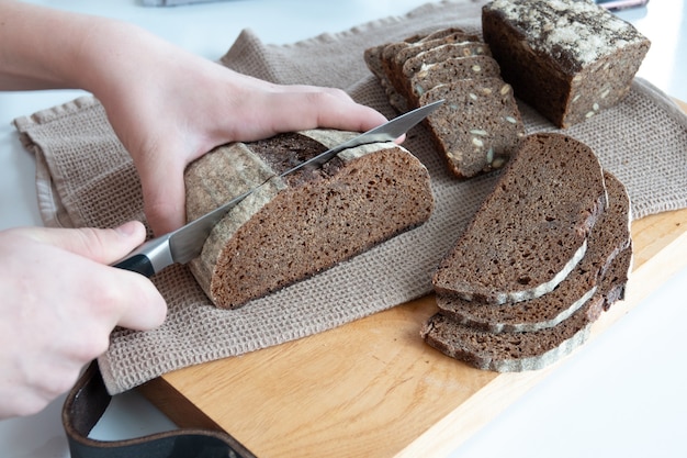 Concepto de pan casero, productos agrícolas naturales, producción nacional. Alimentos orgánicos saludables y sabrosos. Mujer cortando pan integral recién horneado.