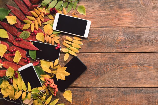 Concepto de pared de madera de hojas de otoño de comercio electrónico. Tecnología de smartphone.