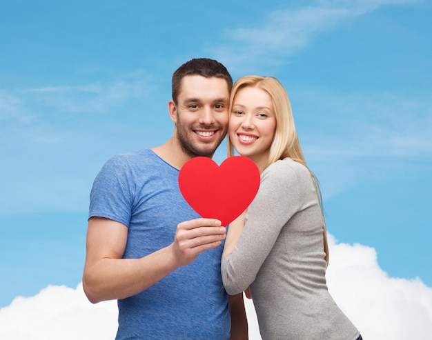 concepto de pareja, amor y familia - pareja sonriente sosteniendo un gran corazón rojo