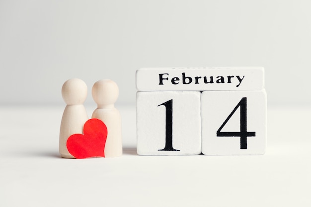 Concepto de una pareja de enamorados junto al calendario catorce de febrero día de San Valentín.