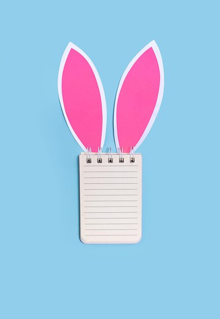 Concepto de Pascua Caderno con espacio para texto con orejas de conejo en un fondo azul