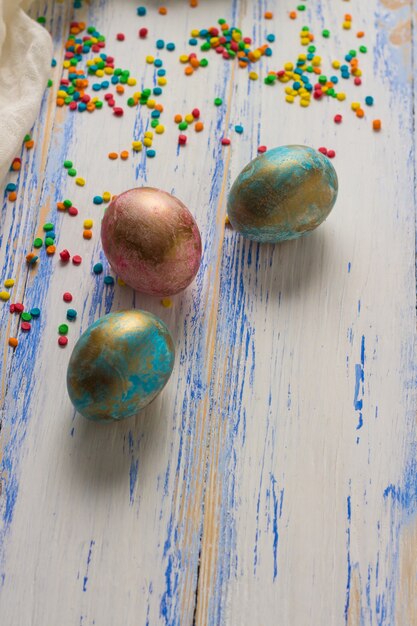 Foto concepto de pascua con huevos de pascua, dulces, tela blanca sobre superficie de madera blanca