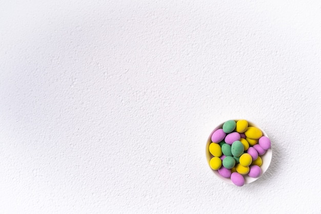 Concepto de pascua. Mini huevos en plato pequeño sobre superficie blanca. Patrón de huevos de color, superficie de Pascua.