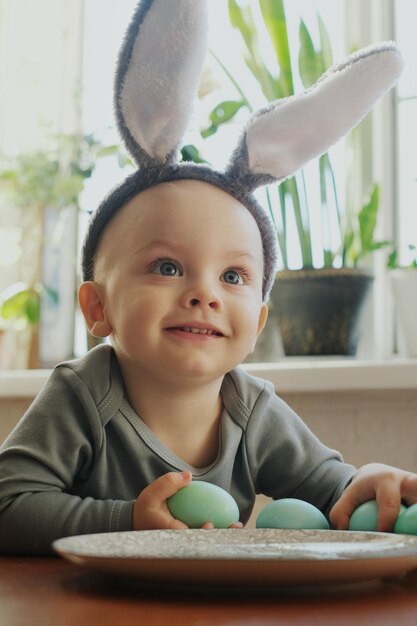 Concepto de Pascua Un niño pequeño lindo sostiene un huevo de Pascua pintado en sus manos