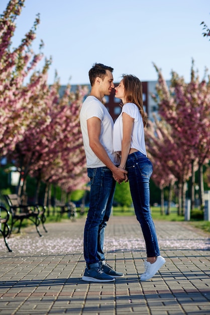 Concepto de pasión y amor. Hombre y mujer besándose en el jardín floreciente en primavera.