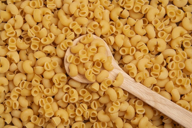 Concepto de pasta las grandes cantidades de pasta de macarrones seca en forma de tubular amarilla cortada clasificadas juntas.