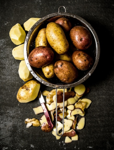 El concepto de patatas mojadas en el colador sobre la mesa de piedra