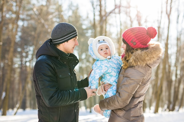Concepto de paternidad, moda, temporada y personas. familia feliz con el niño en ropa de invierno al aire libre