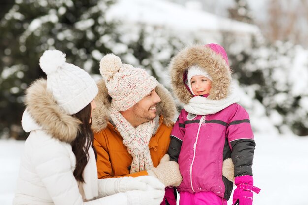 Concepto de paternidad, moda, temporada y personas: familia feliz con niño en ropa de invierno al aire libre