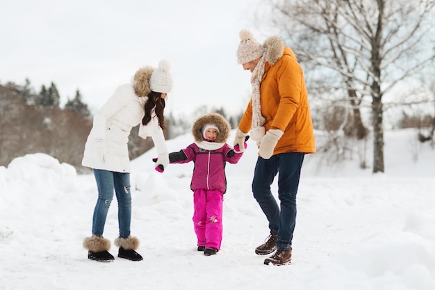 concepto de paternidad, moda, temporada y personas - familia feliz con niños vestidos de invierno caminando al aire libre