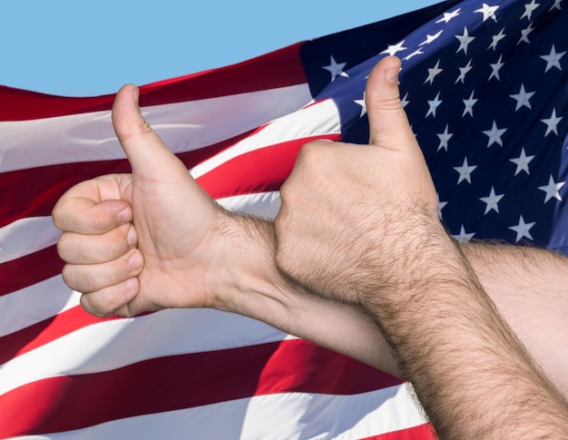 Concepto patriótico. Thumbs up sign contra de la bandera de los Estados Unidos de América