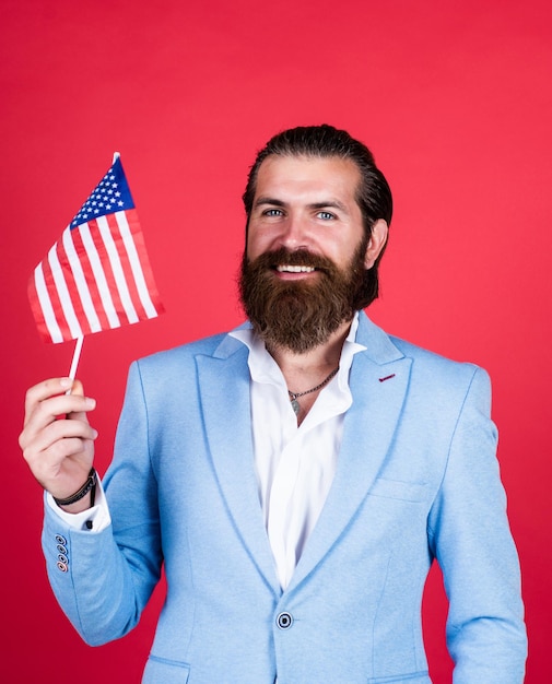 Foto concepto de patriotismo brutal hombre guapo con trabajo de bigote y viaje a estados unidos día de la independencia masculinidad y carisma fiesta formal código de vestimenta político barbudo sostiene bandera estadounidense
