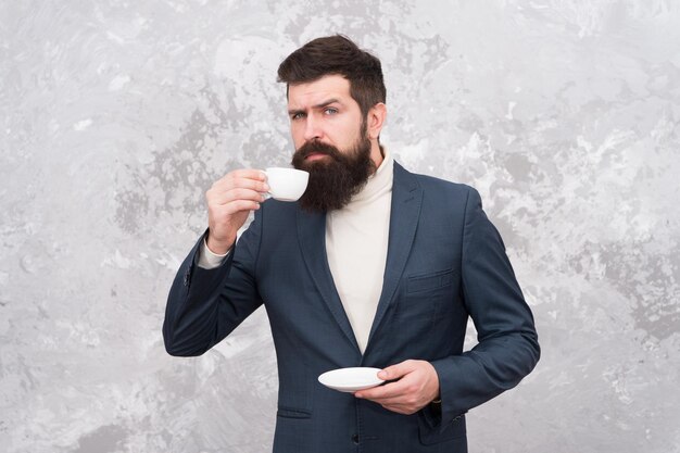 Concepto de pausa para el café Gente de negocios estilo de moda Ropa de estilo casual elegante para la vida de oficina El mejor café servido para él Café de especialidad Hombre apuesto hombre de negocios barbudo sostiene una taza de café