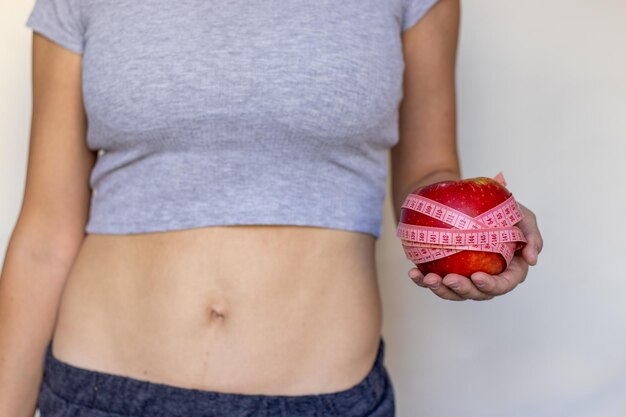 concepto de pérdida de peso mujer en ropa de fitness con cinta métrica de manzana tabletas de pastillas de abeto