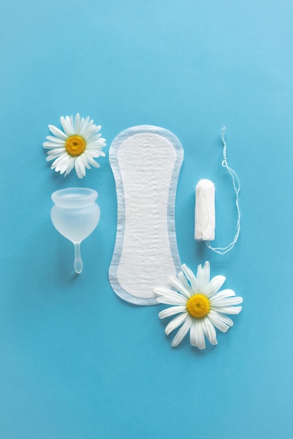 Concepto de período de menstruación Almohadilla femenina blanca higiénica Copa menstrual y tampón con flores de manzanilla Protección de la menstruación Salud de la mujer