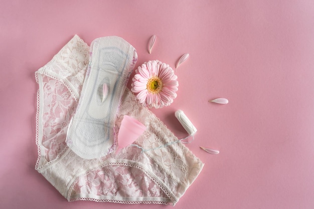 Concepto de período de menstruación Almohadilla femenina blanca higiénica Copa menstrual y tampón con flores rosas Protección de la menstruación Salud de la mujer