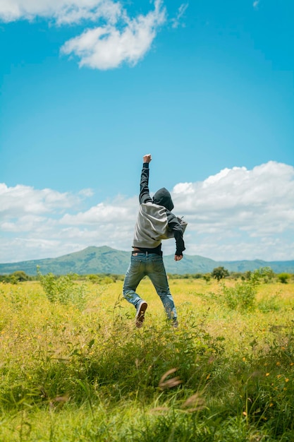 Concepto de una persona libre saltando y levantando el brazo Persona libre saltando de felicidad en el campo hombre de atrás saltando en un bonito campo Vista trasera del hombre saltando en la hierba levantando el puño