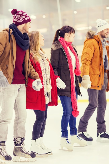 concepto de personas, amistad, deporte y ocio - amigos felices en la pista de patinaje