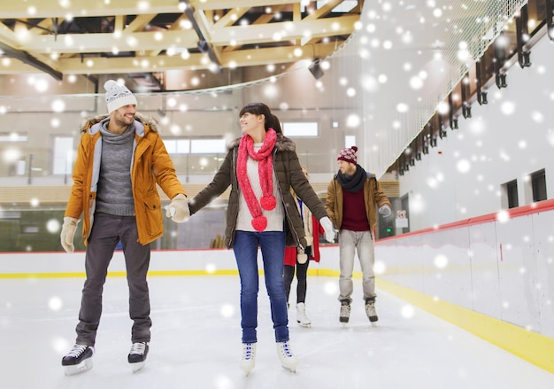 concepto de personas, amistad, deporte y ocio - amigos felices en la pista de patinaje