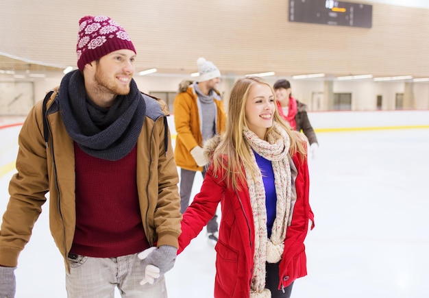 concepto de personas, amistad, deporte y ocio - amigos felices en la pista de patinaje