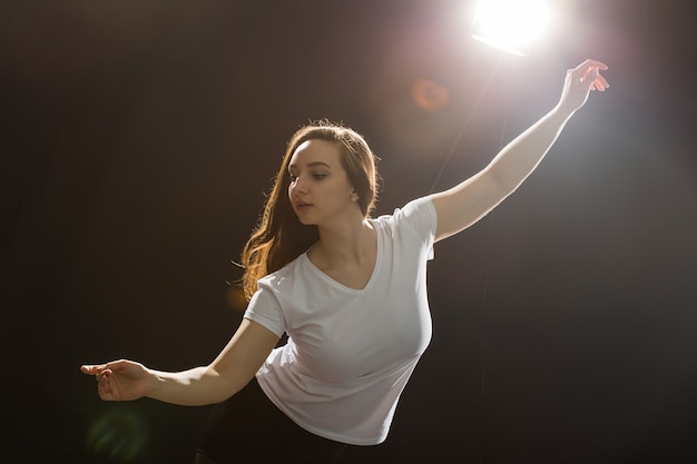 Foto concepto de personas y baile - joven y bella mujer deportiva bailando funk de jazz sobre un fondo negro de estudio.