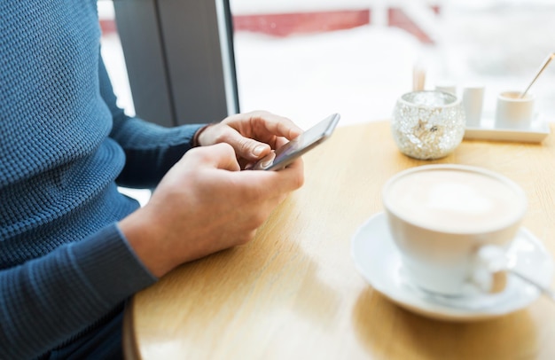 concepto de personas, comunicación y tecnología - primer plano del hombre con smartphones en el café