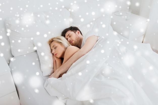 concepto de personas, descanso y relaciones - pareja feliz durmiendo en la cama en casa sobre la nieve