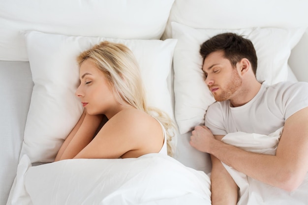 concepto de personas, descanso y relaciones - pareja feliz durmiendo en la cama en casa