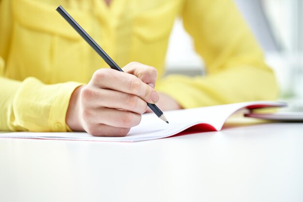 concepto de personas y educación - cierre de manos femeninas escribiendo en un cuaderno en la escuela