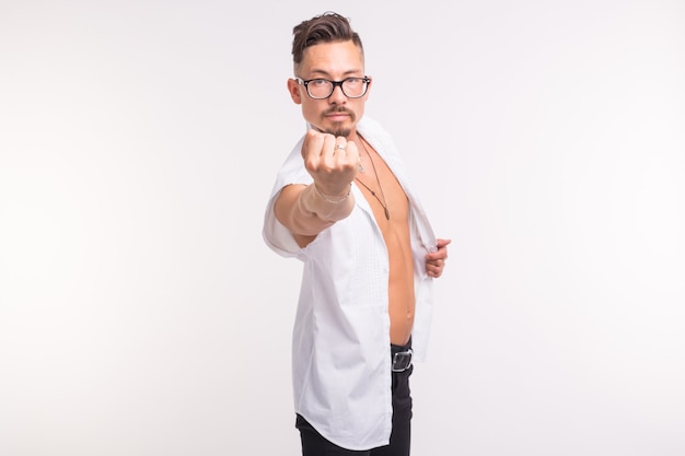 Concepto de personas, emociones y gestos - hombre guapo con camisa blanca mostrando su puño en blanco