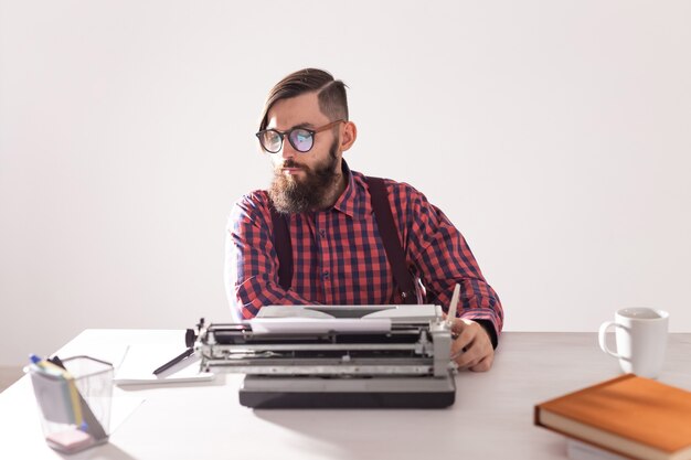 Concepto de personas, escritor y hipster - joven escritor elegante trabajando en máquina de escribir.