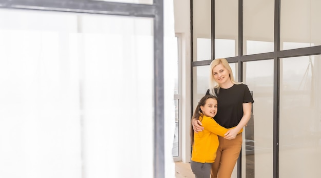 concepto de personas y familia, niña sonriente feliz con madre abrazándose en casa.