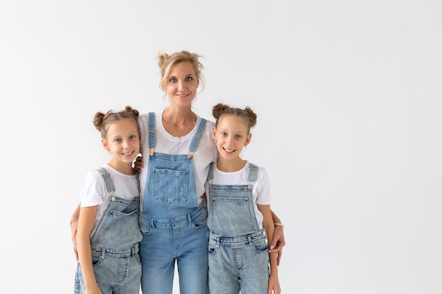 Concepto de personas, familia y niños - hermanas gemelas con su mamá en la pared blanca con espacio de copia.