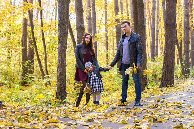 Concepto de personas, familia y ocio - familia divirtiéndose de pie en el parque de otoño