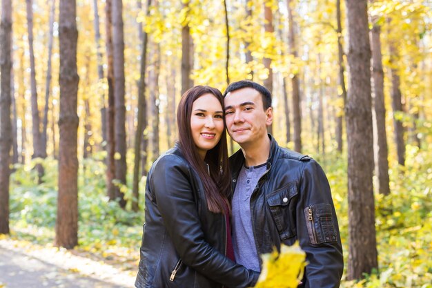 Concepto de personas, familia y ocio - pareja joven divirtiéndose en el parque de otoño.