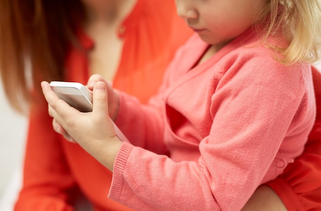 concepto de personas, familia y tecnología - primer plano de mujer y niña con smartphone