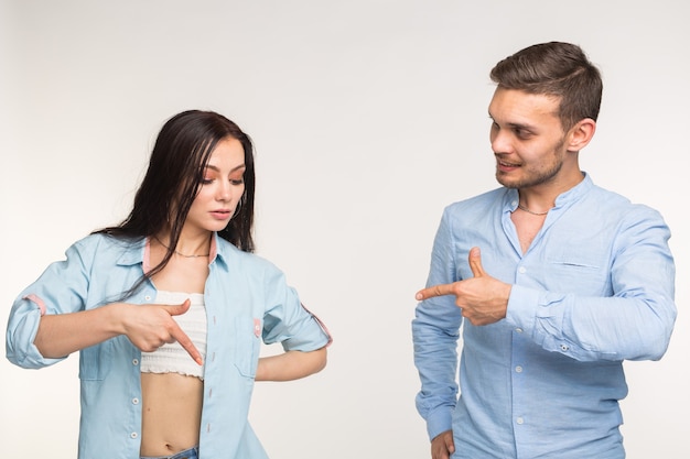 Concepto de personas y gestos - joven mujer bonita y guapo apuntando hacia abajo sobre fondo blanco.