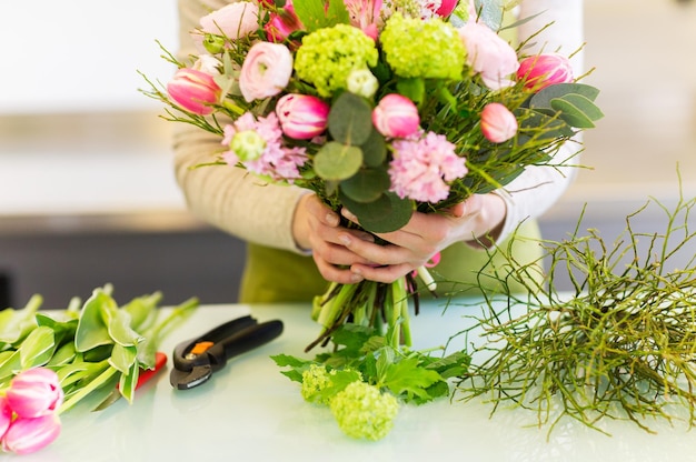 concepto de personas, negocios, venta y floristería - cierre de una mujer florista haciendo un montón en la floristería