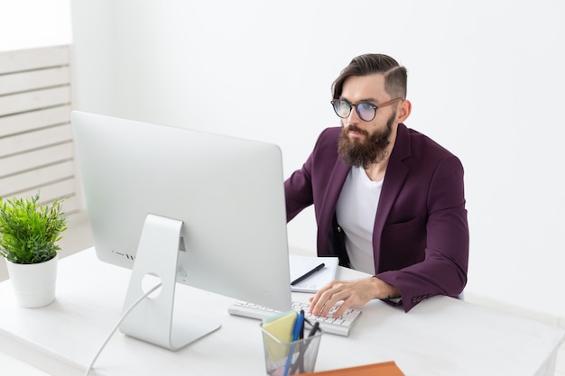 Concepto de personas y tecnología guapo con barba trabajando en la computadora