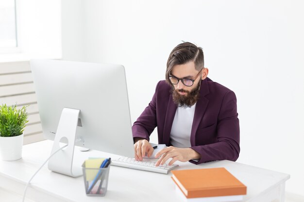 Concepto de personas y tecnología hombre atractivo con barba trabajando en la computadora