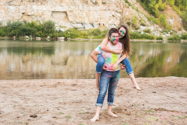 Concepto de personas, turismo y naturaleza - Pareja sonriente con caras pintadas divirtiéndose.