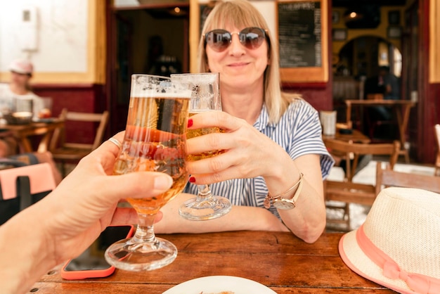 Concepto de personas y vacaciones primer plano de una mujer sonriente sosteniendo un vaso de cerveza lager y brindando